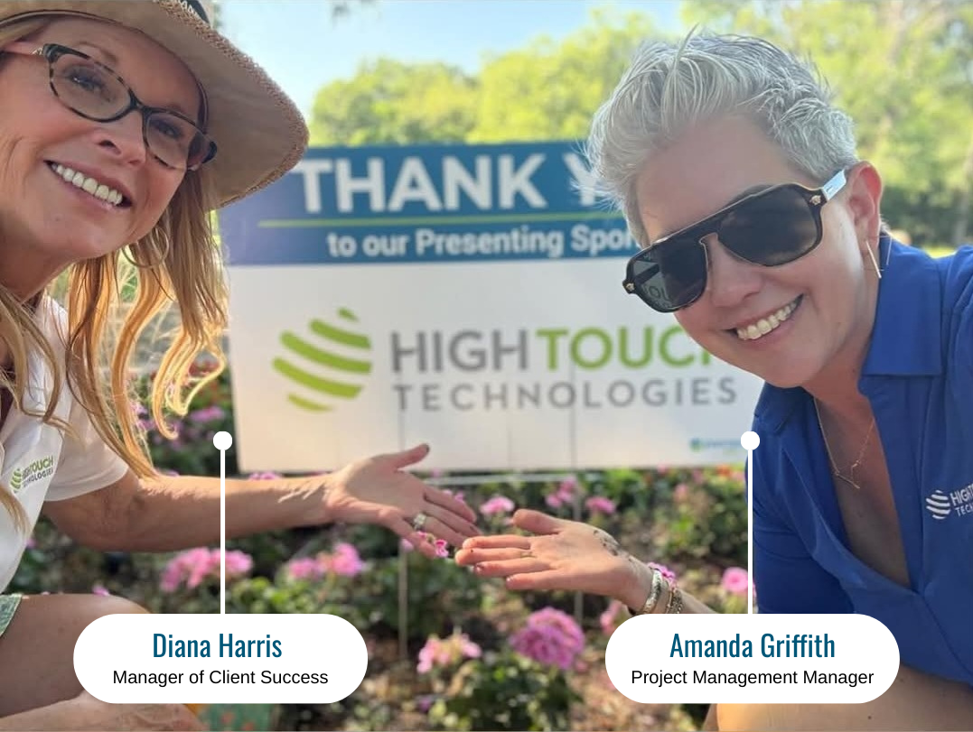 Diana Harris and Amanda Griffith from High Touch Technologies smile in front of the sponsor sign at the 2025 Envision Dallas Golf Fore Vision Tournament, highlighting High Touch’s role as Presenting Sponsor.